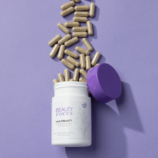 Beauty Focus multivitamin container with purple lid and scattered capsules on a purple background